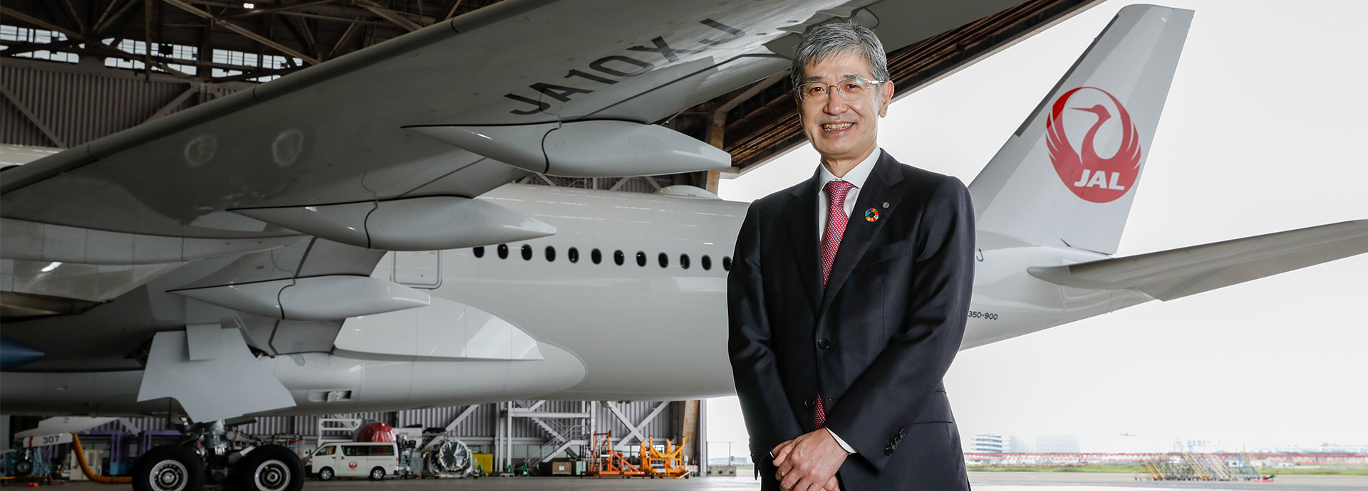空港内日本航空機を背景とした社長の写真画像