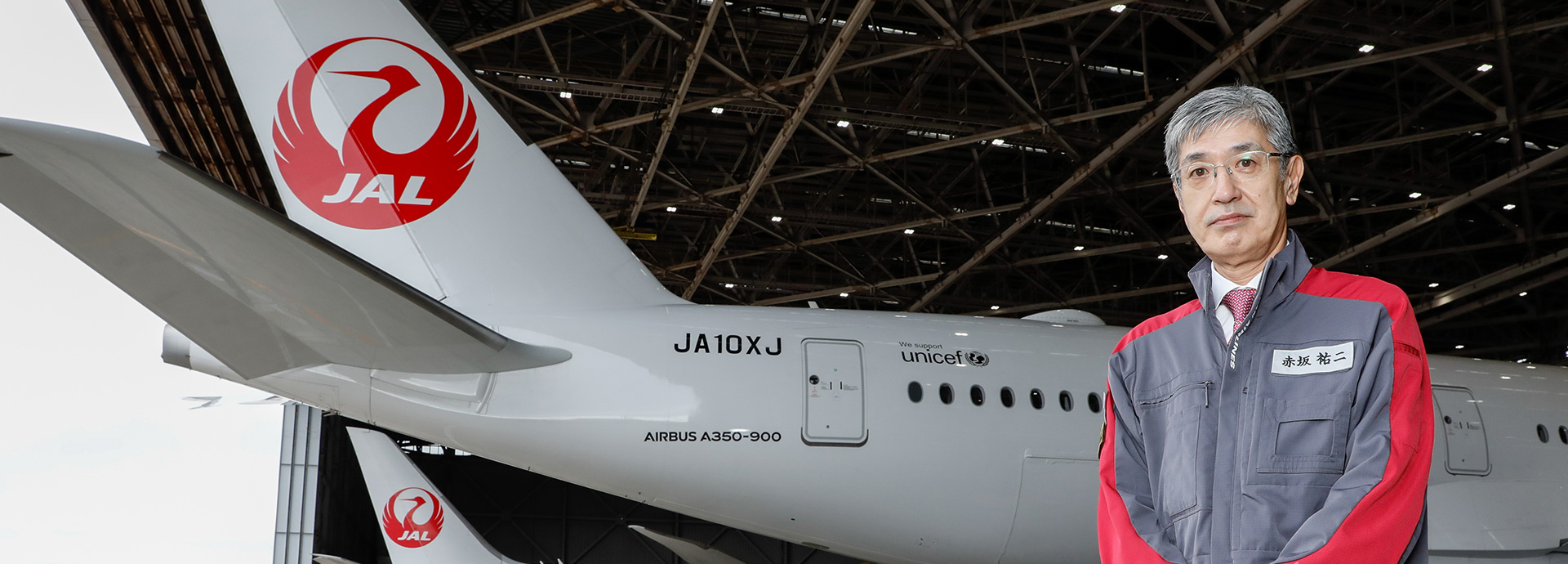 空港内日本航空機を背景とした社長の写真画像