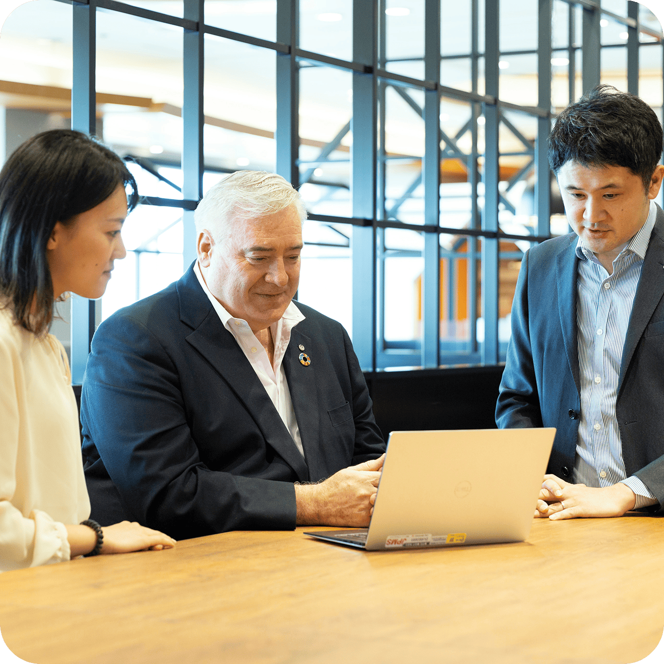Employees having a meeting around a laptop computer.