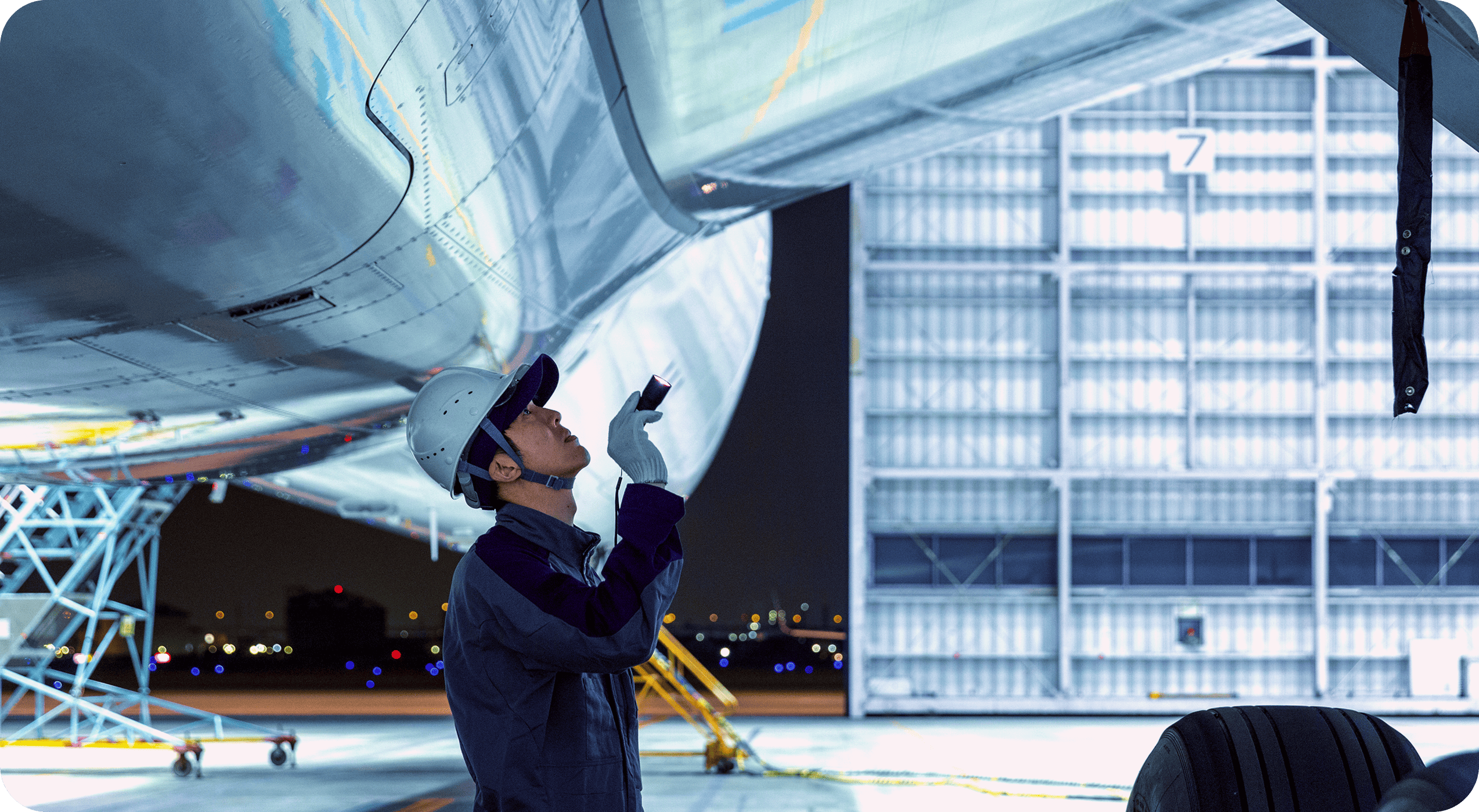夜間の空港で、飛行機を点検する男性整備士