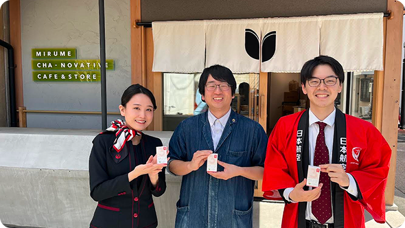 商品を持って微笑む客室乗務員と地域企業のスタッフたち