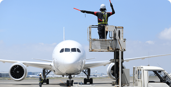 空港にて高い位置から飛行機を誘導するグランドハンドリングスタッフ